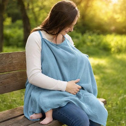 Cape d'allaitement bleue portée par une maman sur un banc.